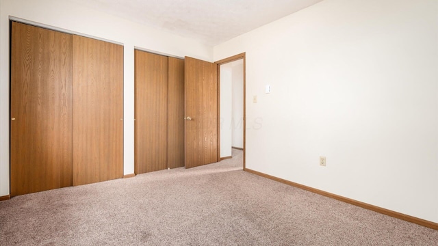 unfurnished bedroom with carpet flooring and two closets