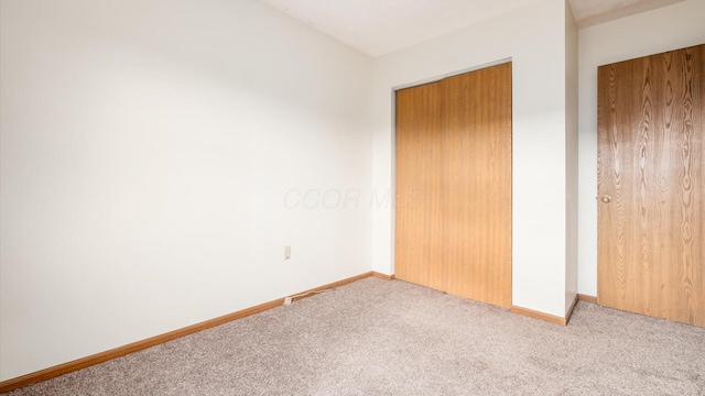 unfurnished bedroom with light carpet and a closet