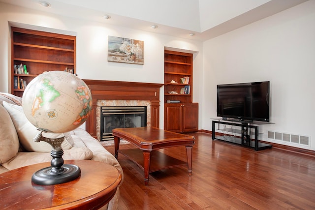 living room with a fireplace, hardwood / wood-style floors, and built in features