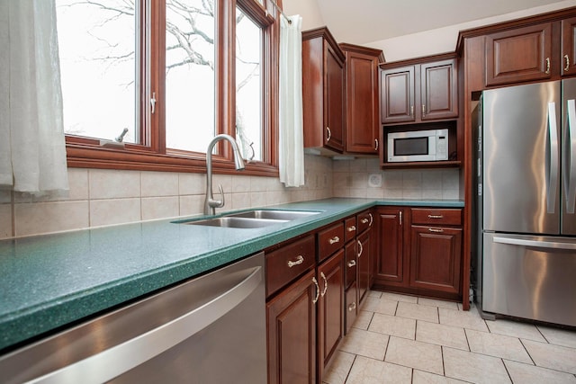 kitchen featuring backsplash, a healthy amount of sunlight, sink, and appliances with stainless steel finishes