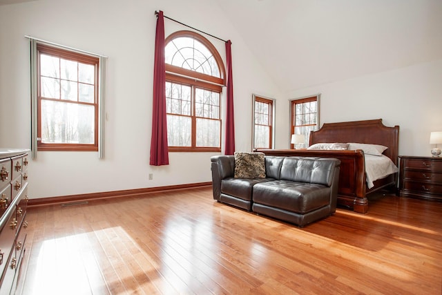 bedroom featuring wood-type flooring, high vaulted ceiling, and multiple windows