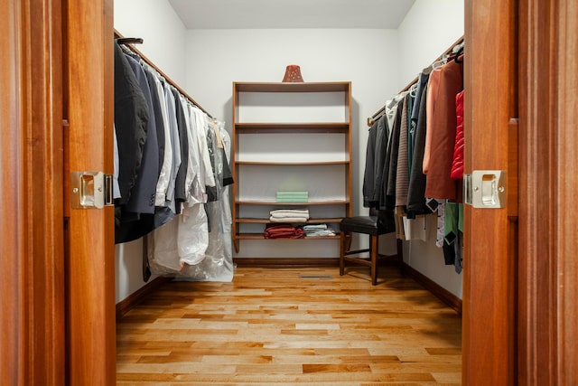 walk in closet with light hardwood / wood-style flooring