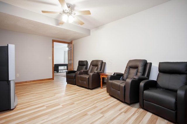 cinema room with light hardwood / wood-style floors and ceiling fan