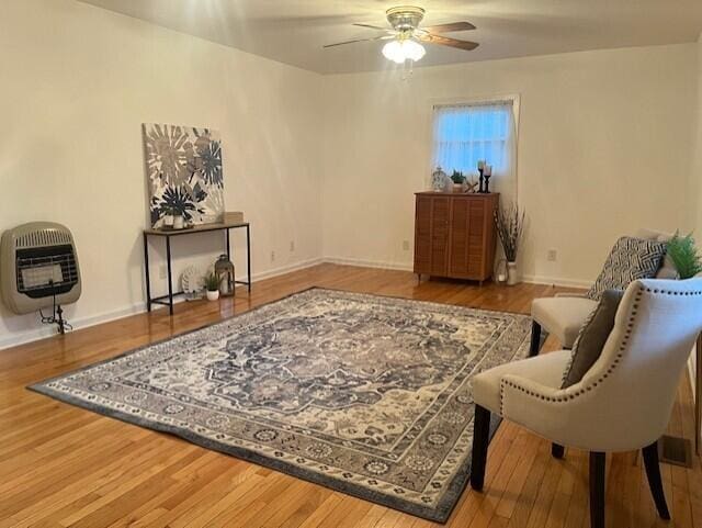 living area featuring ceiling fan, wood-type flooring, and heating unit