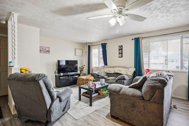 living room featuring ceiling fan, a textured ceiling, and light wood-type flooring