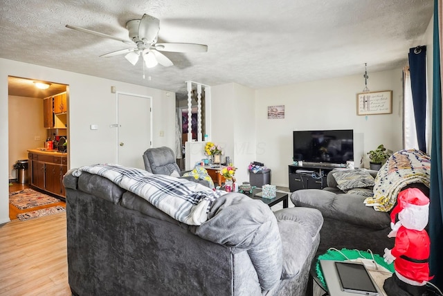 living room with ceiling fan, wood-type flooring, and a textured ceiling