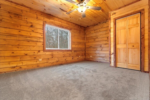 unfurnished bedroom featuring carpet flooring, ceiling fan, wooden ceiling, and wood walls