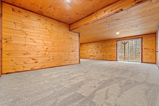 carpeted spare room featuring wooden ceiling and wooden walls