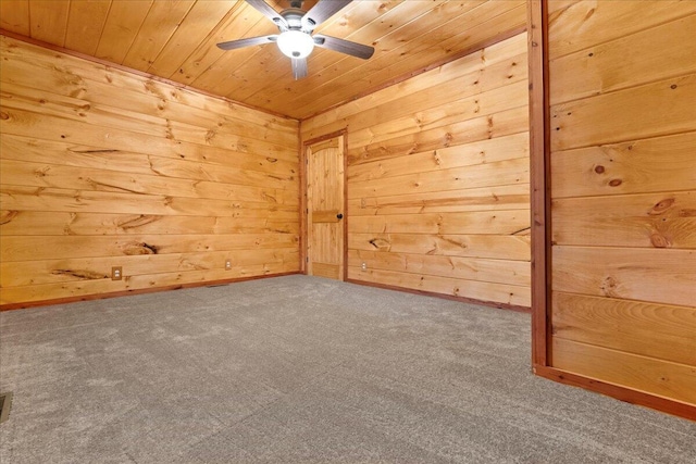 spare room with carpet, ceiling fan, wooden walls, and wood ceiling