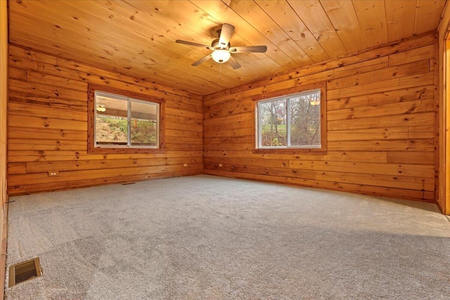 carpeted empty room with plenty of natural light, wooden ceiling, and wood walls