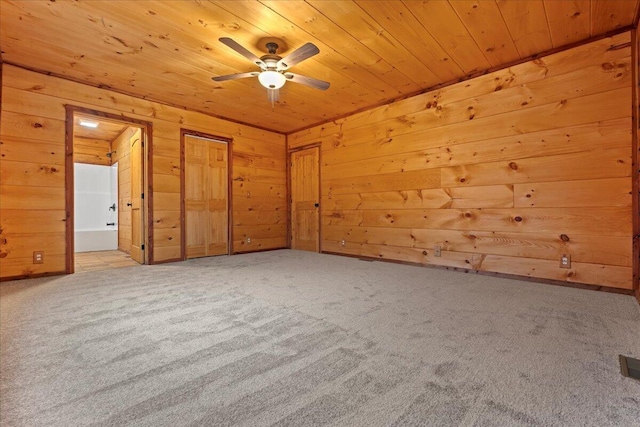 unfurnished bedroom with wood walls, ceiling fan, light colored carpet, and wooden ceiling