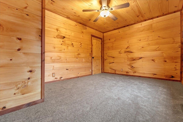 empty room featuring carpet, wooden ceiling, ceiling fan, and wooden walls