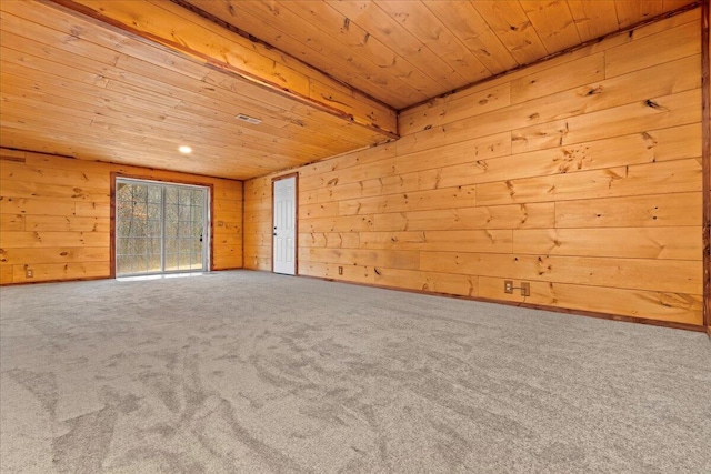 carpeted spare room with wooden ceiling and wood walls