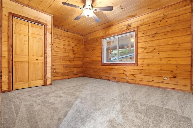 unfurnished bedroom with ceiling fan, wooden walls, wooden ceiling, carpet floors, and a closet