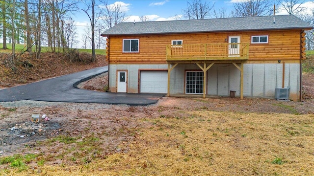 back of property featuring a garage, cooling unit, and a deck