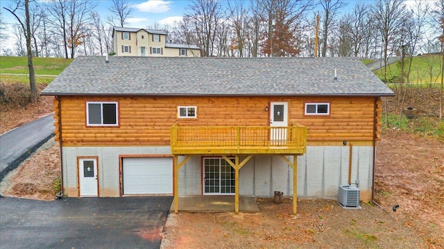 exterior space with a wooden deck, cooling unit, and a garage