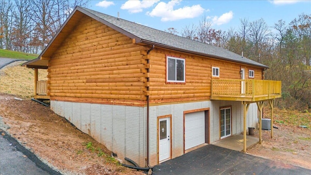 view of side of home with a garage and central air condition unit