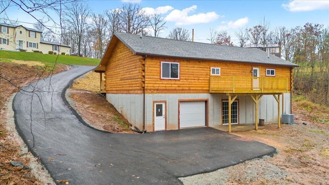 exterior space with a garage, a wooden deck, and central AC