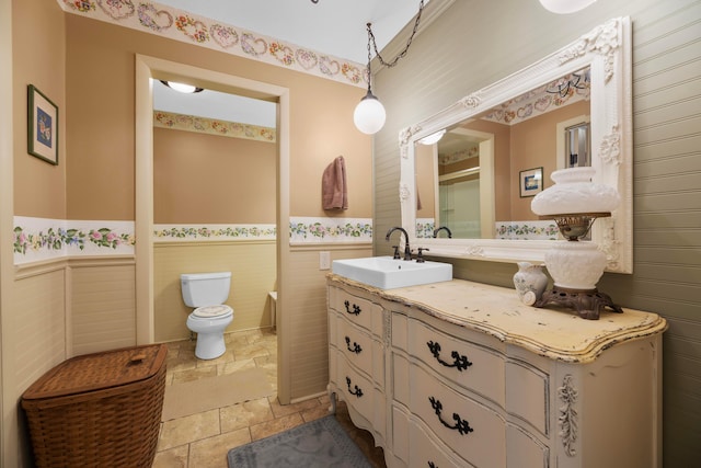 bathroom with vanity, toilet, and tile walls