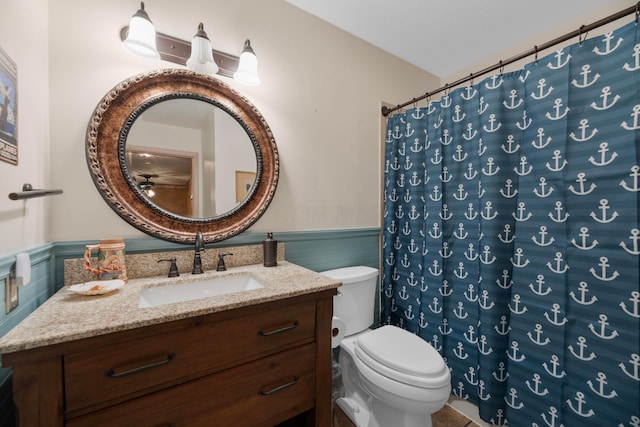 bathroom with a shower with shower curtain, vanity, toilet, and tile walls