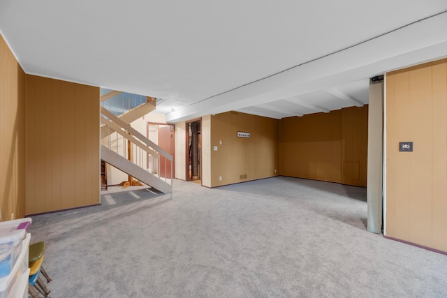 basement featuring light carpet and wood walls