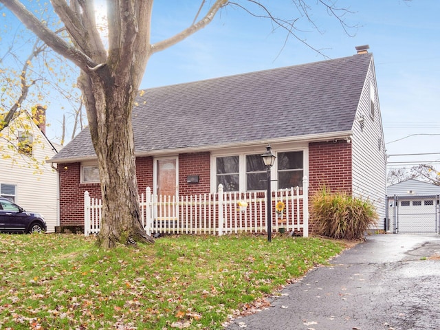 view of front of house featuring a garage, a front lawn, and an outdoor structure