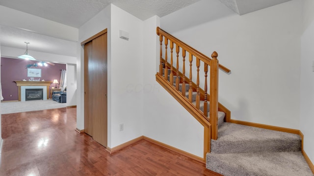 stairs with wood-type flooring and a textured ceiling