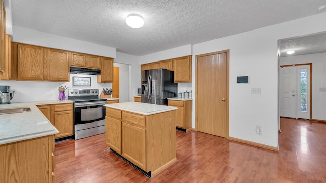 kitchen with a textured ceiling, a center island, light wood-type flooring, and stainless steel appliances