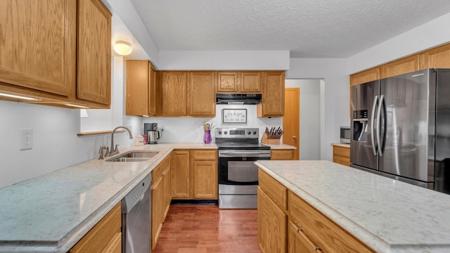 kitchen with light stone counters, a textured ceiling, stainless steel appliances, dark wood-type flooring, and sink