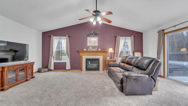 carpeted living room with ceiling fan, lofted ceiling, and a tile fireplace