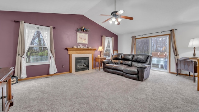 living room featuring carpet flooring, vaulted ceiling, ceiling fan, and a tiled fireplace