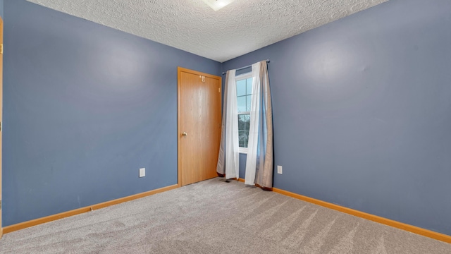 carpeted empty room featuring a textured ceiling