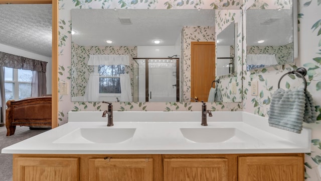 bathroom with a shower with door, vanity, and a textured ceiling