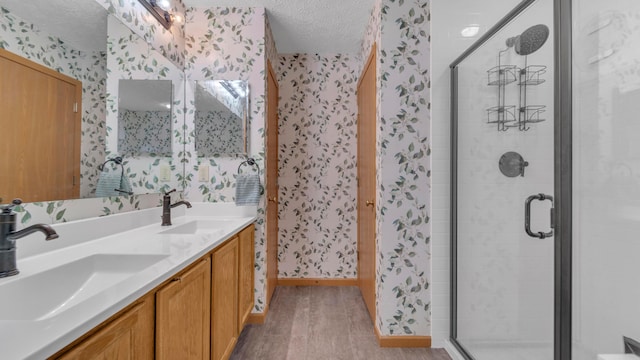 bathroom featuring vanity, an enclosed shower, and a textured ceiling