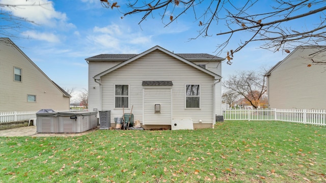 rear view of house featuring a lawn, central air condition unit, and a hot tub