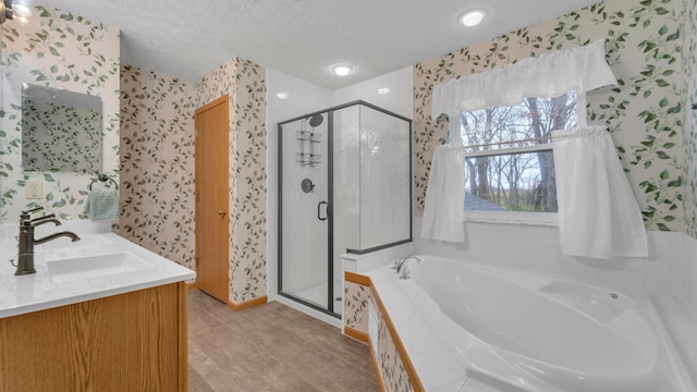 bathroom with vanity, shower with separate bathtub, and a textured ceiling