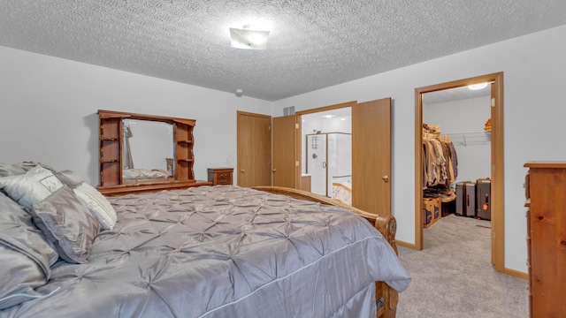 bedroom featuring light carpet, a textured ceiling, a spacious closet, and a closet