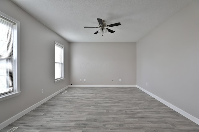 empty room with ceiling fan, a healthy amount of sunlight, and light wood-type flooring