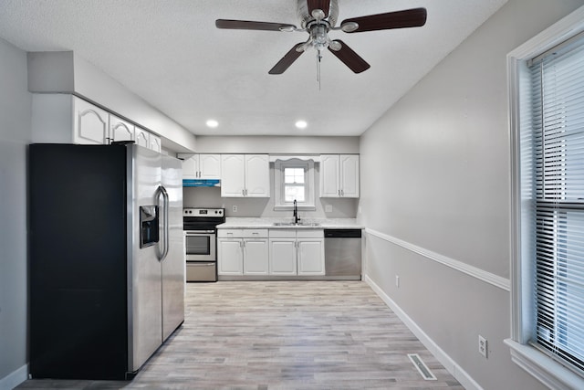 kitchen with ceiling fan, sink, light hardwood / wood-style floors, white cabinets, and appliances with stainless steel finishes