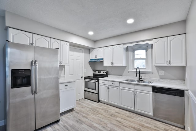 kitchen featuring appliances with stainless steel finishes, a textured ceiling, sink, light hardwood / wood-style flooring, and white cabinetry