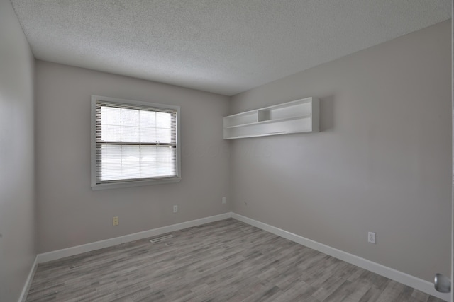 empty room with light hardwood / wood-style floors and a textured ceiling