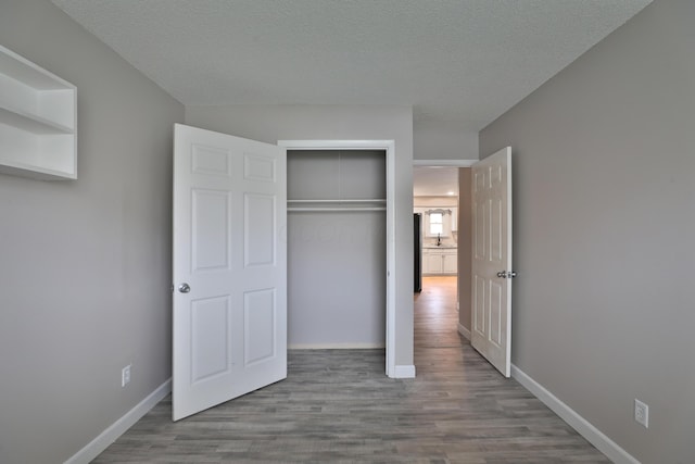 unfurnished bedroom featuring light hardwood / wood-style floors, a textured ceiling, and a closet