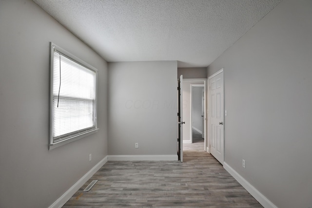 empty room featuring a textured ceiling and light hardwood / wood-style flooring