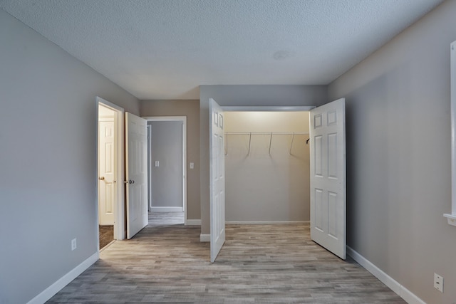 unfurnished bedroom featuring a closet, light hardwood / wood-style floors, and a textured ceiling