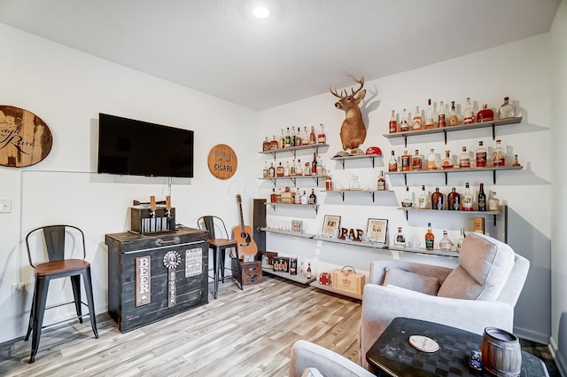 living room featuring indoor bar and light hardwood / wood-style flooring