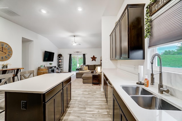 kitchen with ceiling fan, sink, light hardwood / wood-style flooring, a kitchen island, and lofted ceiling