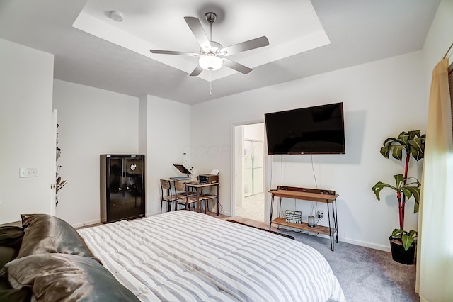 carpeted bedroom with a raised ceiling and ceiling fan