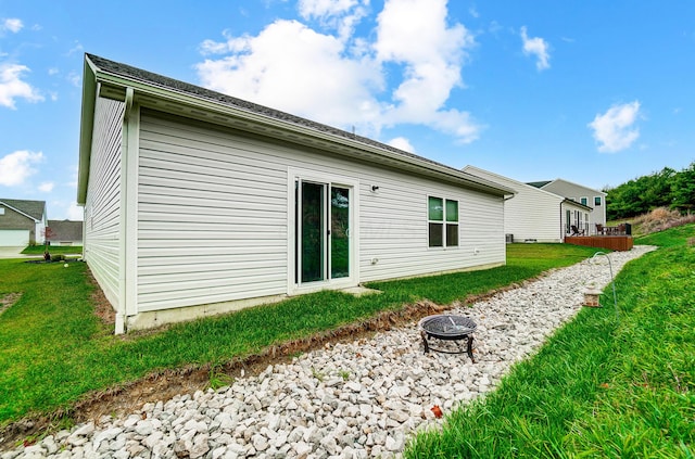 back of house with a yard and a fire pit