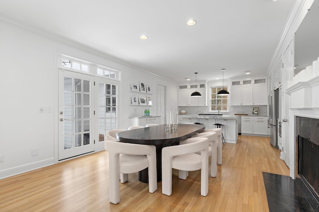 dining space with crown molding, light hardwood / wood-style floors, and french doors