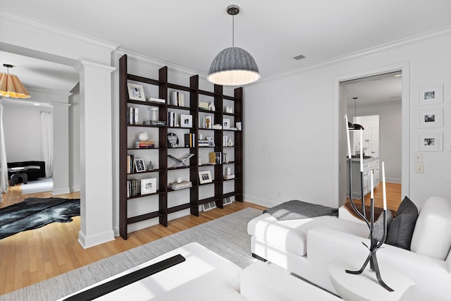 living area featuring ornamental molding, decorative columns, and light hardwood / wood-style flooring